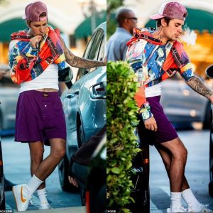 Justin Bieber bares a tattooed arm with his hoodie pulled halfway over his shoulder as he indulges in a smoke break with The Kid LAROI in LA